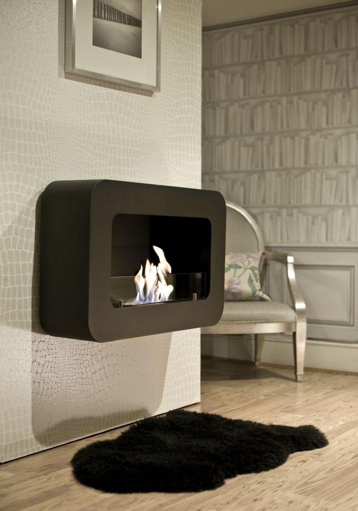 Against the background of a white and silver wall, a black hinged fireplace with rounded corners looks a good contrast