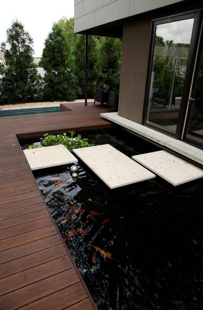 Pond by the house with a wooden edge and a white stone tiled bridge