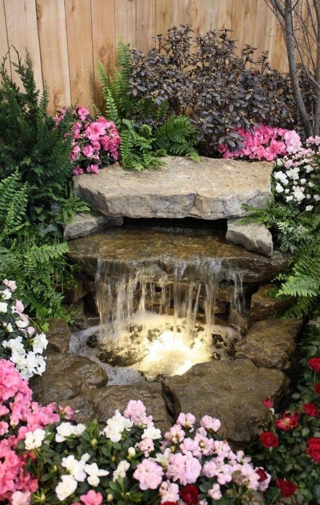 Small pond with a waterfall surrounded by a flower arrangement